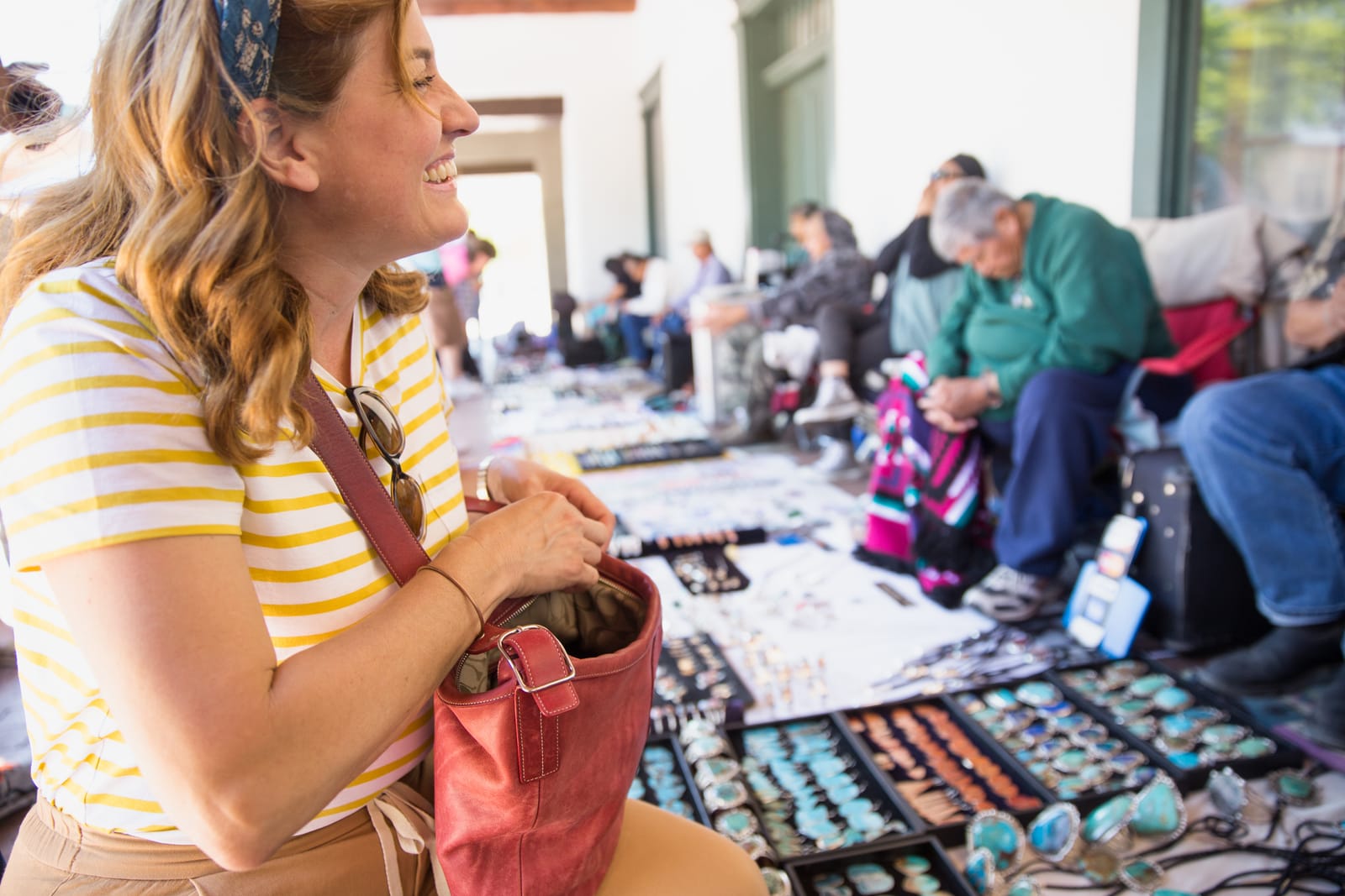 A shopper buys handmade jewelry from a vendor at an outdoor market